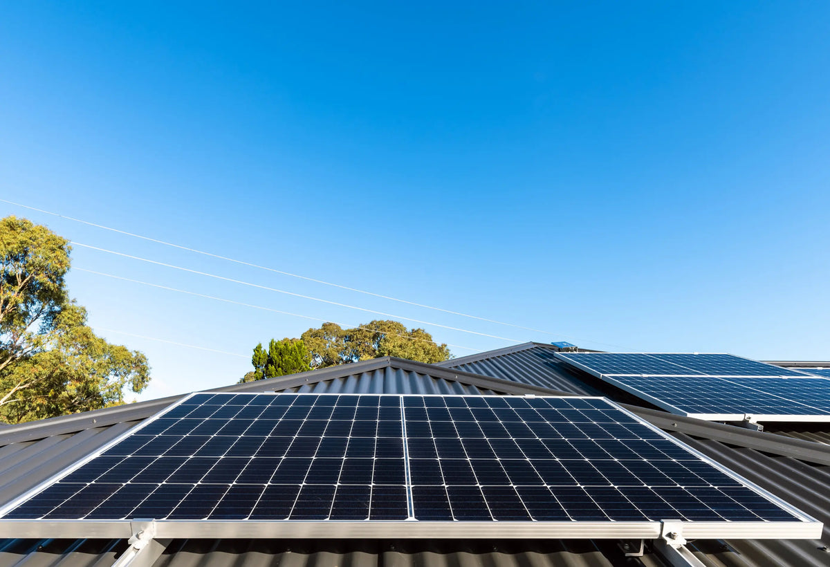 Solarmodule auf einem Hausdach bei sonnigem Wetter mit blauem Himmel – moderne Photovoltaikanlage zur nachhaltigen Stromerzeugung.