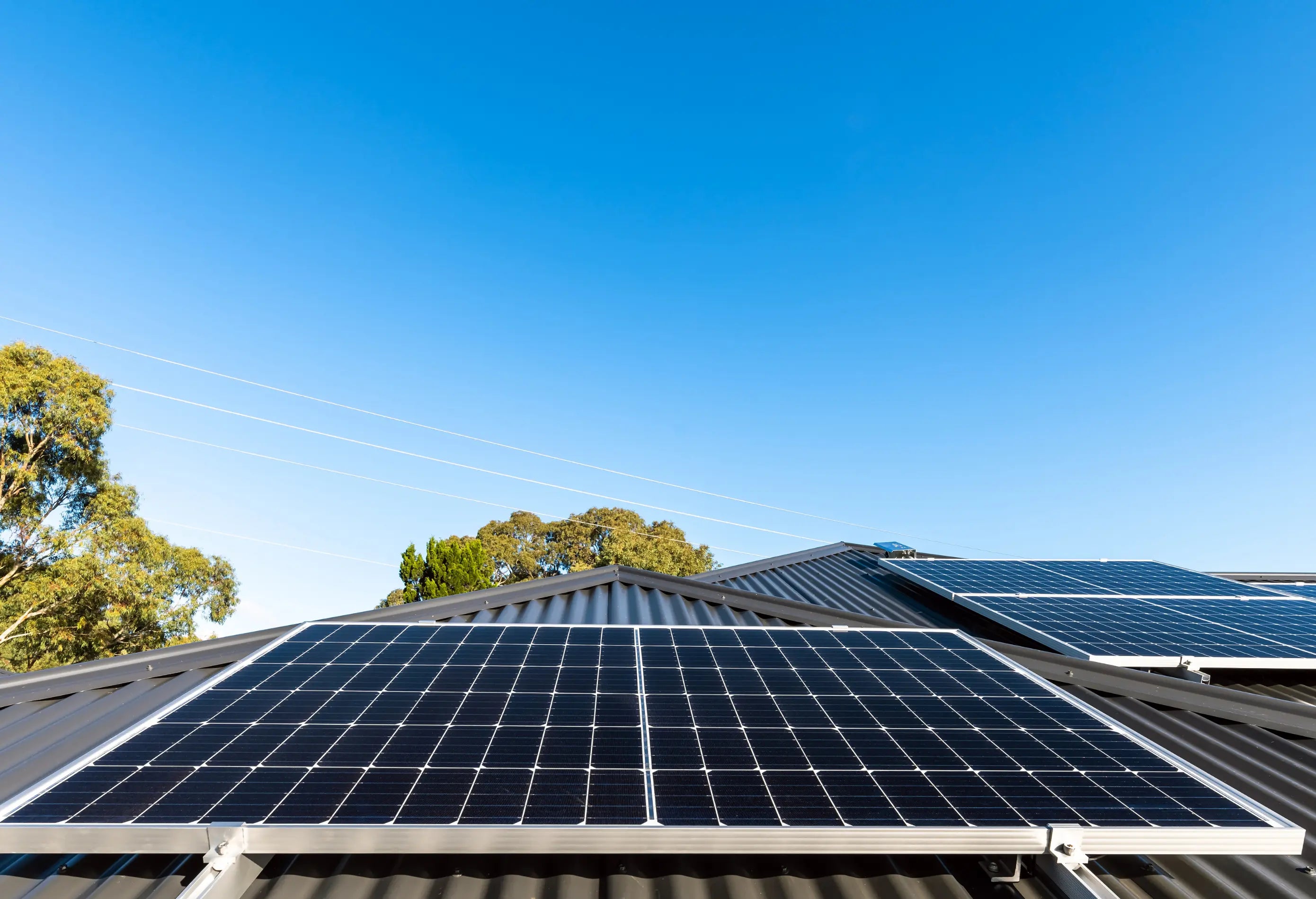 Solarmodule auf einem Hausdach bei sonnigem Wetter mit blauem Himmel – moderne Photovoltaikanlage zur nachhaltigen Stromerzeugung.