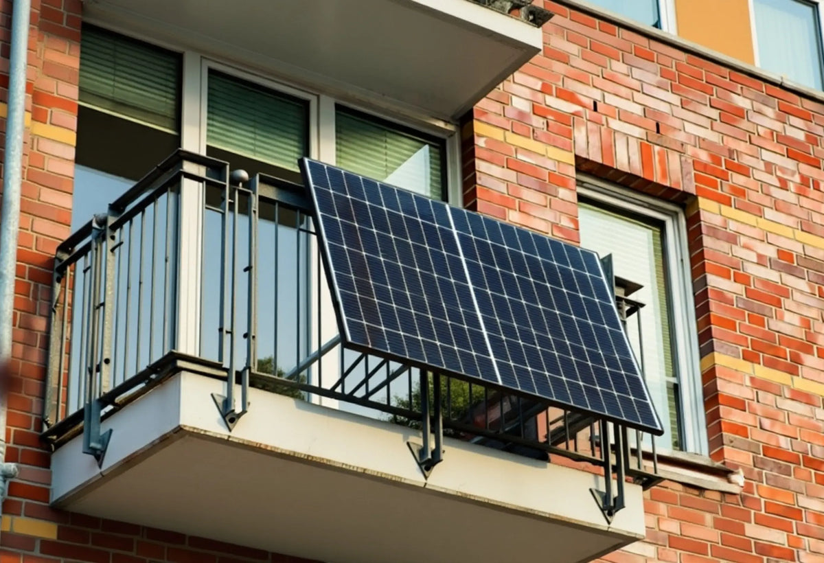 Balkonkraftwerk mit Solarpanels auf einem Wohnungsbalkon, die Module sind an der Brüstung montiert und werden von direkter Sonneneinstrahlung beleuchtet, moderne Mini-Solaranlage zur Stromerzeugung im urbanen Umfeld