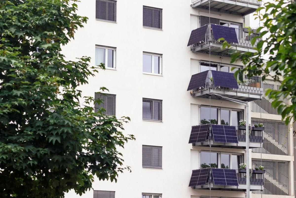 Mehrfamilienhaus mit Solarpanels an Balkongeländern